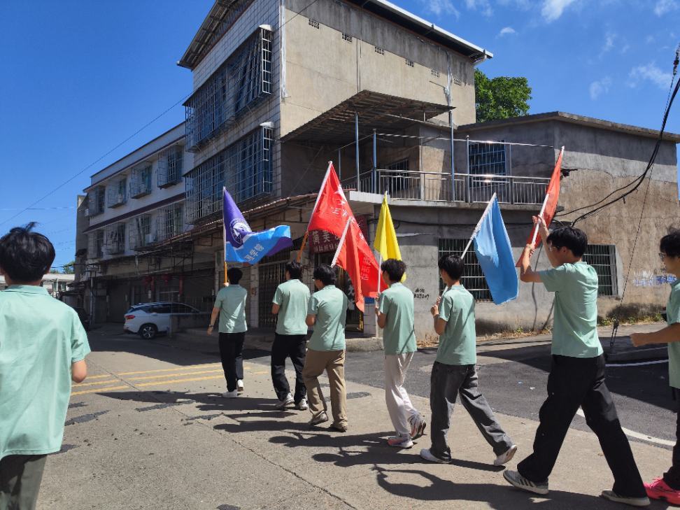 志愿者高举队旗沿着乡镇道路行进,奔赴乡村支教第一线