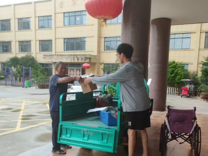 图为实践团成员为老人搬运物资